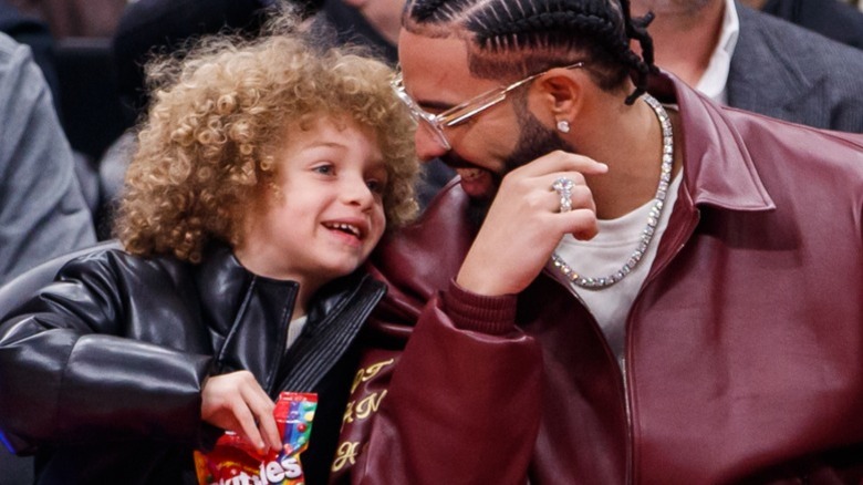 Drake et Adonis chuchotant lors d'un match de basket