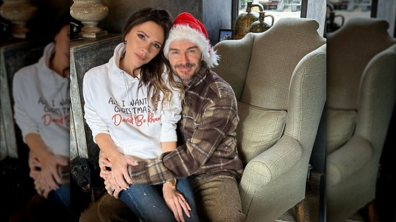 Victoria Beckham assise sur les genoux de David Beckham