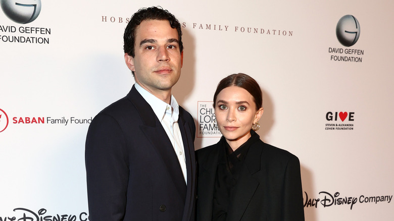 Louis Eisner et Ashley Olsen posent des costumes noirs sur le tapis rouge