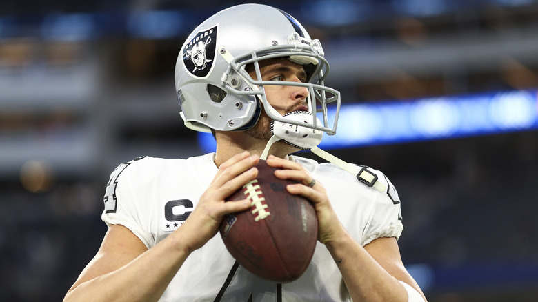 Derek Carr en uniforme Raider avec ballon de football