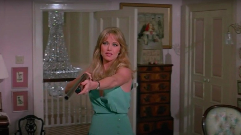 Tanya Roberts pointant un fusil de chasse