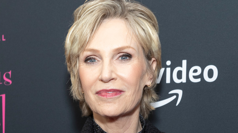 Jane Lynch cheveux blonds bouche fermée sourire lèvres roses