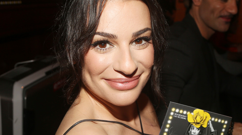 Lea Michele bouche fermée sourire cheveux noirs ondulés couleur de lèvre neutre