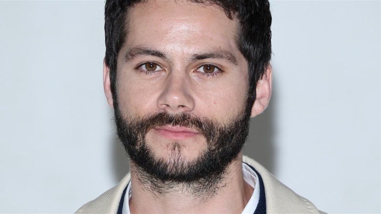 Dylan O'Brien mur blanc barbe débraillée, regardant la caméra