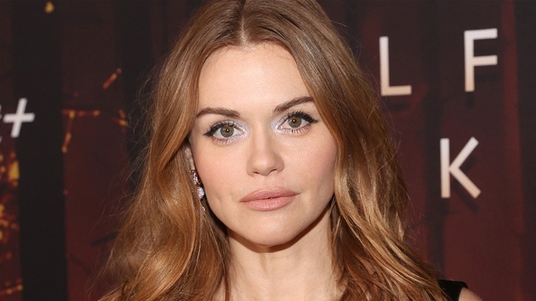 Holland Roden cheveux roux fond rouge, regardant la caméra