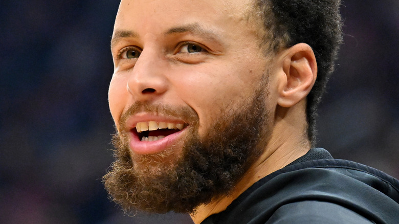 Steph Curry sourit sur le terrain lors d'un match NBA 2023