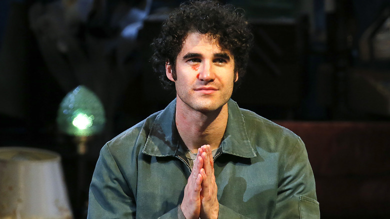 Darren Criss avec les mains en prière, regardant