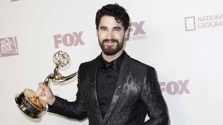 Darren Criss souriant, tenant un Emmy Award 