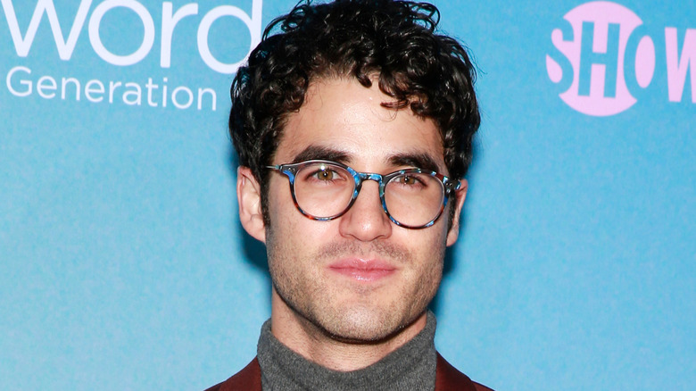 Darren Criss souriant, portant des lunettes