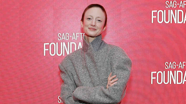 Andrea Riseborough souriante, les bras croisés