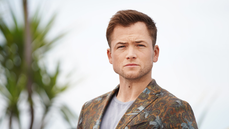 Taron Egerton posant à l'extérieur en costume