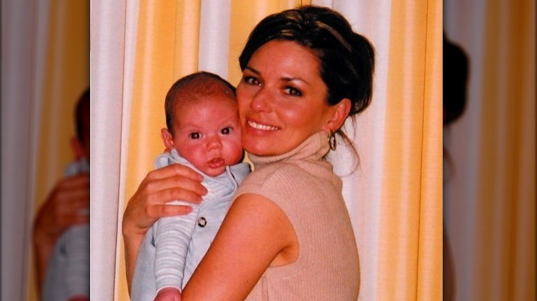 Shania Twain tenant son bébé, Eja Lange, et souriant