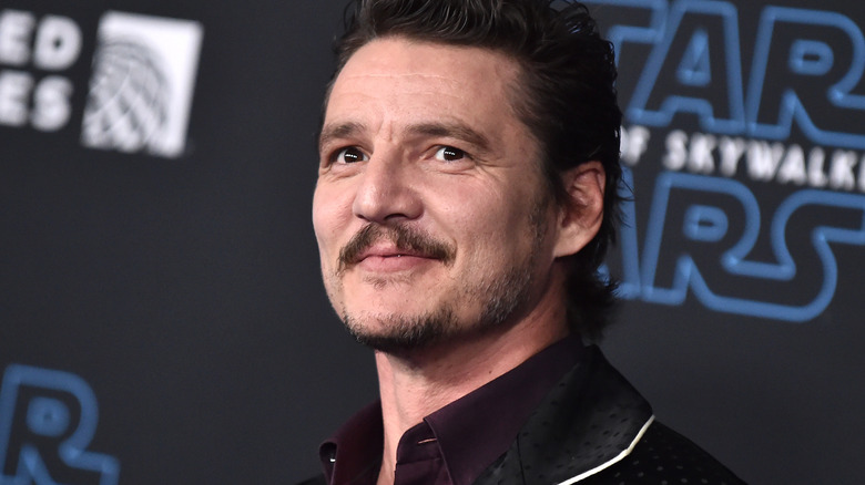 Pedro Pascal levant les yeux, souriant