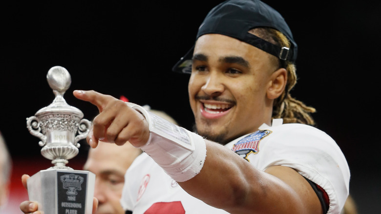 Jalen Hurts tient le trophée en pointant du doigt et en souriant