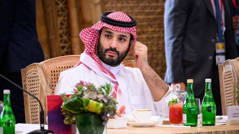 Mohammed ben Salmane regarde de côté en se grattant l'oreille