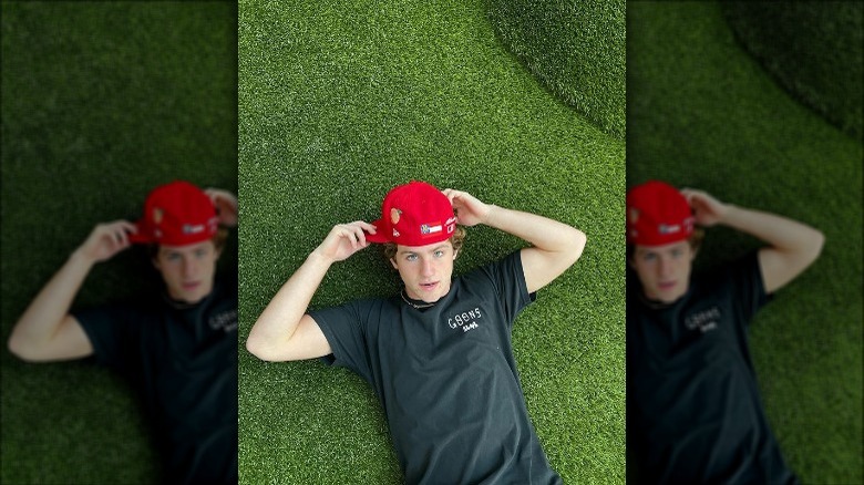 MattyBRaps allongé sur l'herbe avec une casquette de baseball en 2022