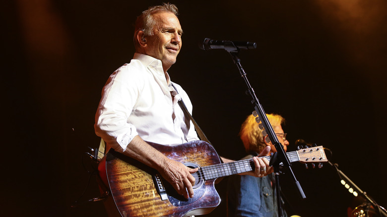 Kevin Costner chante et joue de la guitare sur scène