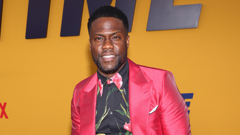 Kevin Hart portant un costume rose, posant