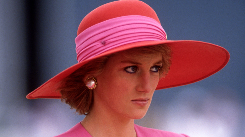 La princesse Diana lors d'un événement, à l'air solennelle, chapeau rose et rouge