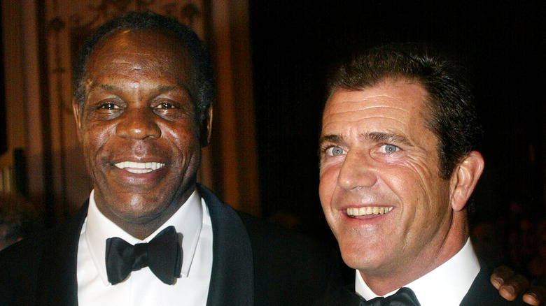 Danny Glover et Mel Gibson souriants en smoking