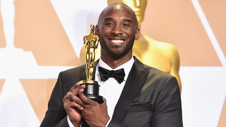 Kobe Bryant souriant et tenant un Oscar