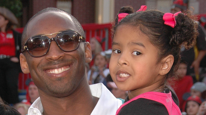 Kobe Bryant souriant avec des lunettes de soleil tout en tenant Natalia Bryant