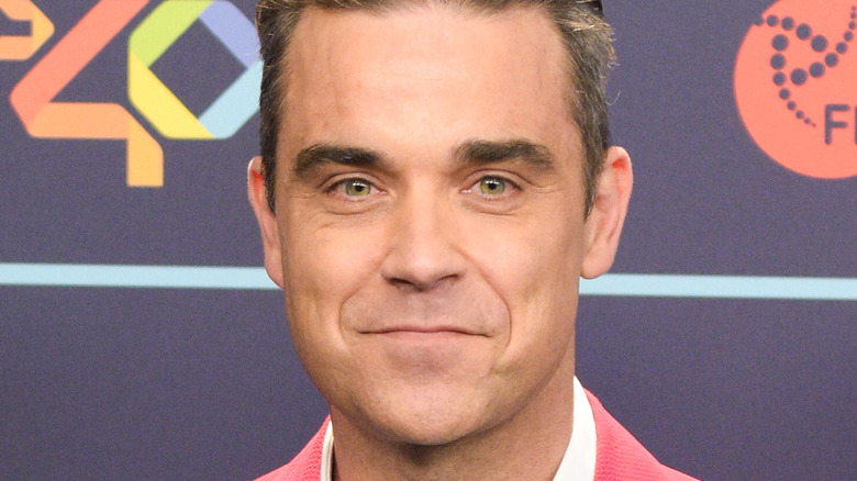 Robbie Williams souriant sur le tapis rouge