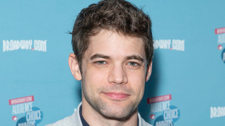 Jeremy Jordan sur un tapis rouge, souriant doucement