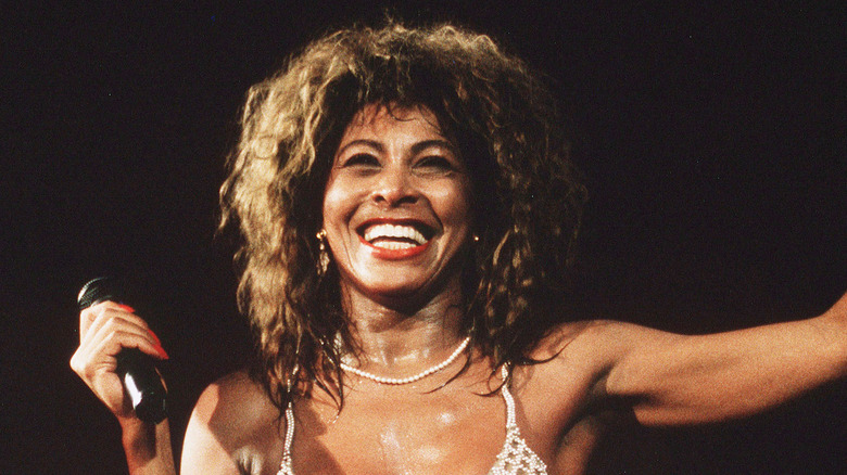 Tina Turner avec un large sourire chantant sur scène 