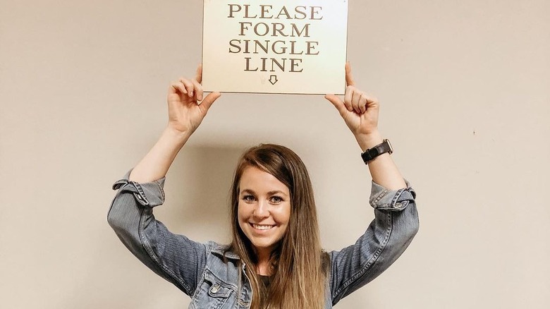 Jana Duggar tient une pancarte au-dessus de la tête