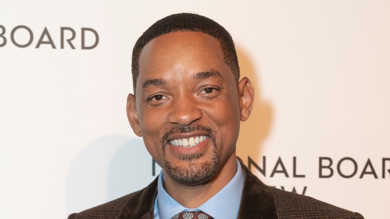 Will Smith sourit en costume à carreaux