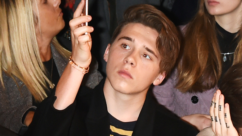 Brooklyn Beckham regarde son téléphone