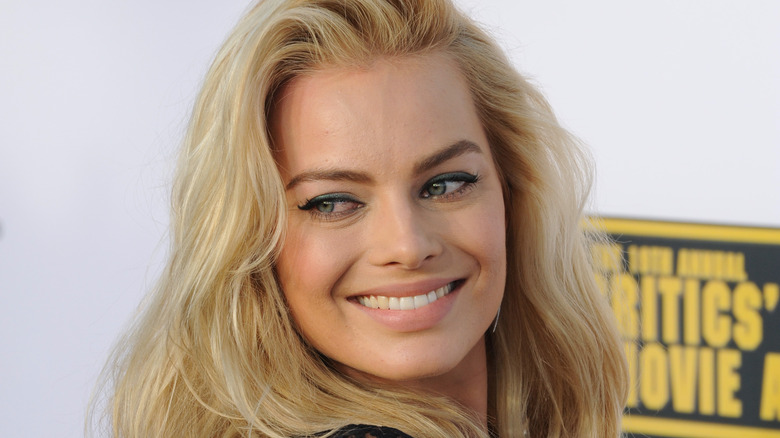 Margot Robbie souriant par-dessus son épaule