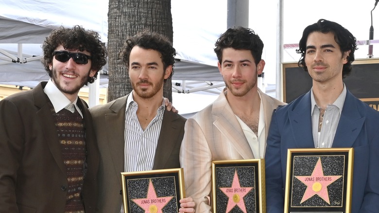 Frankie posant avec ses frères alors que Kevin, Nick et Joe détiennent des stars hollywoodiennes