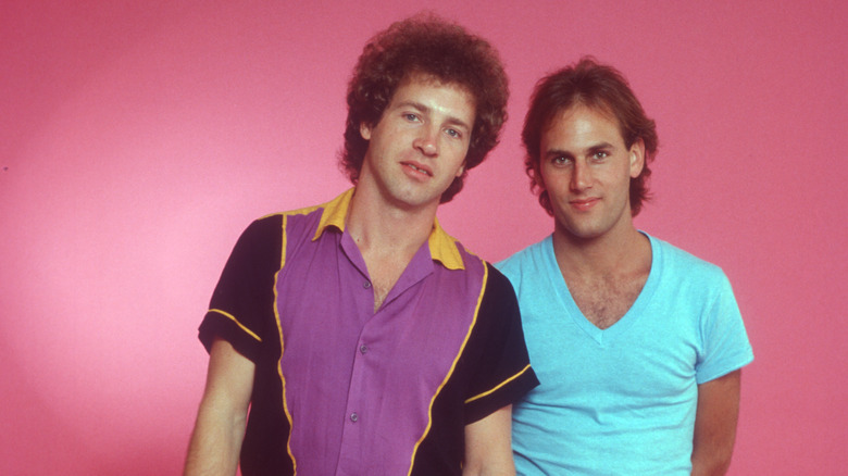 Membres de Tommy Tutone posant ensemble devant un fond rose