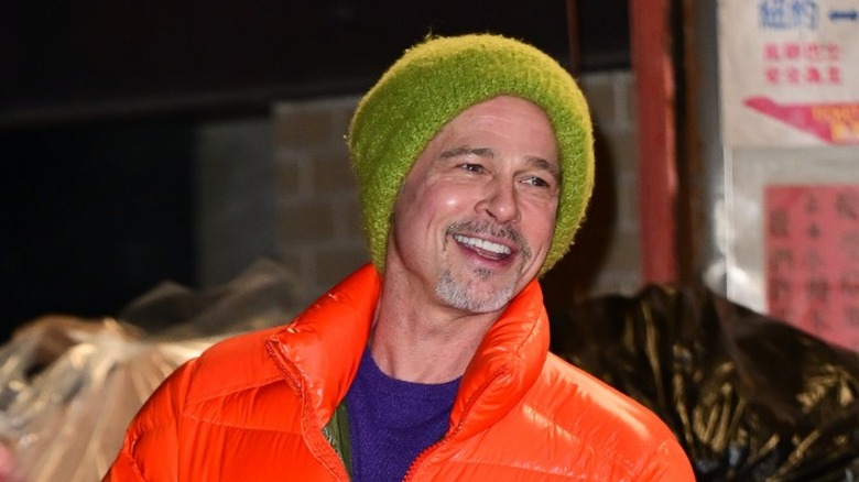 Brad Pitt porte une veste orange avec un chapeau vert