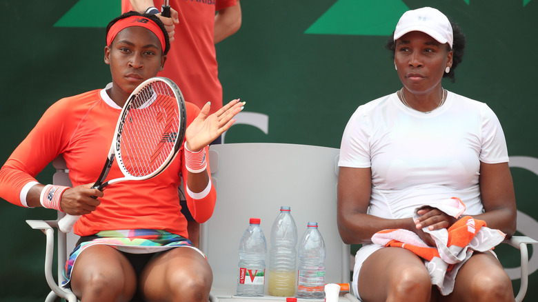 Coco Gauff assise et tenant une raquette à côté de Venus Williams