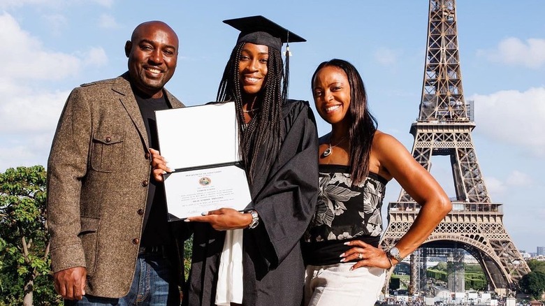 Coco Gauff portant une casquette et adulte debout avec ses parents posant avec son diplôme devant la Tour Eiffel