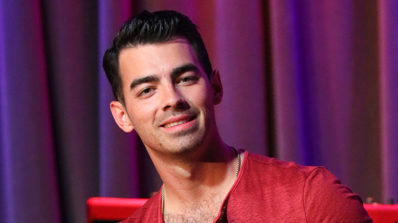 Joe Jonas assis sur une chaise 