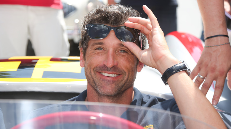 Patrick Dempsey dans une voiture enlevant ses lunettes de soleil de son visage 