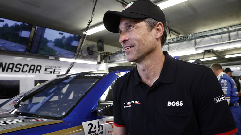 Patrick Dempsey devant une voiture de course