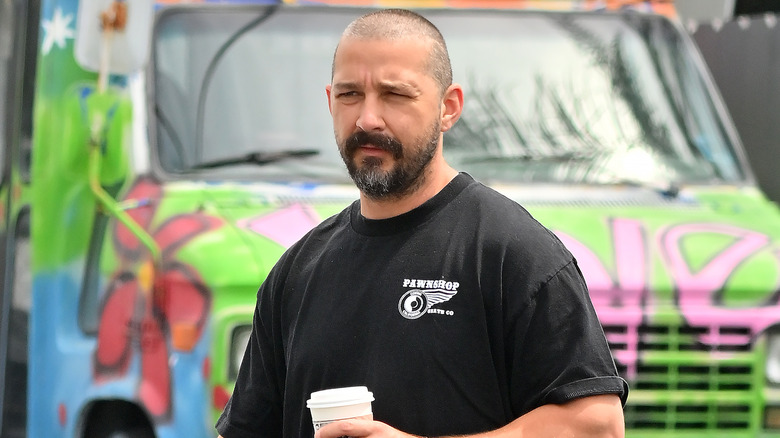 Shia LaBeouf marchant avec une tasse de café