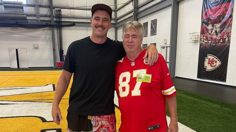 Travis Kelce souriant avec un bras autour d'Ed Kelce