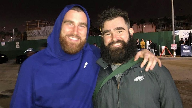 Travis Kelce souriant avec un bras autour de Jason Kelce