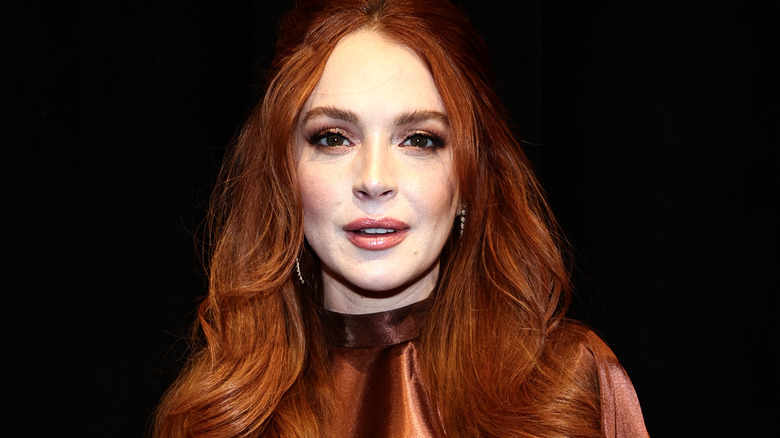 Lindsay Lohan souriante dans une robe bronze