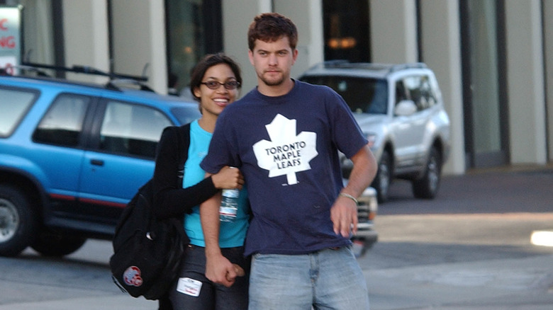 Rosario Dawson et Joshua Jackson sourient et marchent ensemble sur le trottoir