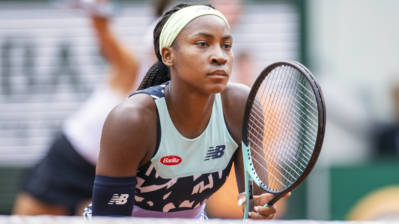 Coco Gauff debout sur le court de tennis, tenant sa raquette prête à jouer