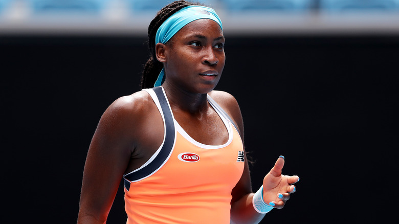 Coco Gauff porte un haut orange et un bandeau bleu clair