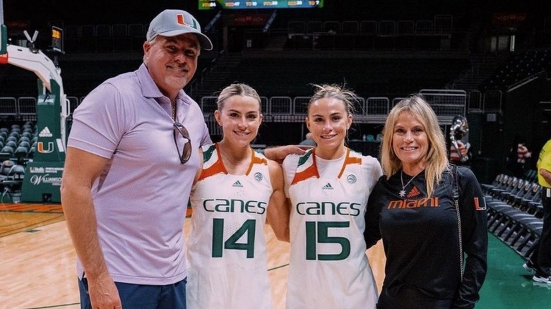 Les jumeaux Cavinder dans leurs uniformes de Miami souriants à côté de leurs parents.