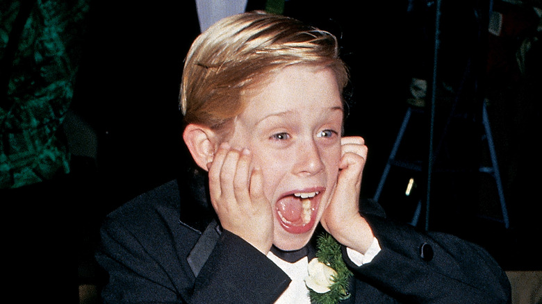 Macaulay Culkin posant avec les mains sur le visage